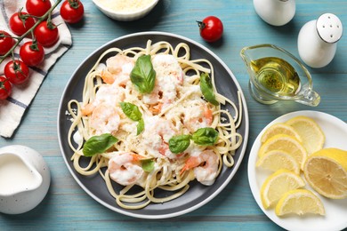 Photo of Tasty pasta with shrimps served on light blue wooden table, flat lay