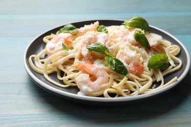 Photo of Tasty pasta with shrimps on light blue wooden table, closeup