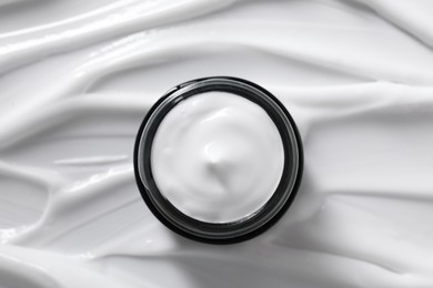 Photo of Face cream in jar on cosmetic product, top view