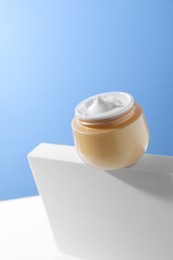 Stylish presentation of face cream in jar against light blue background