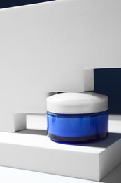 Stylish presentation of face cream in jar against blue background