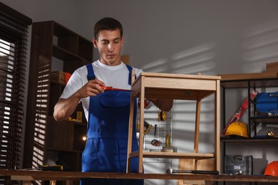 Man repairing wooden stool with screwdriver indoors