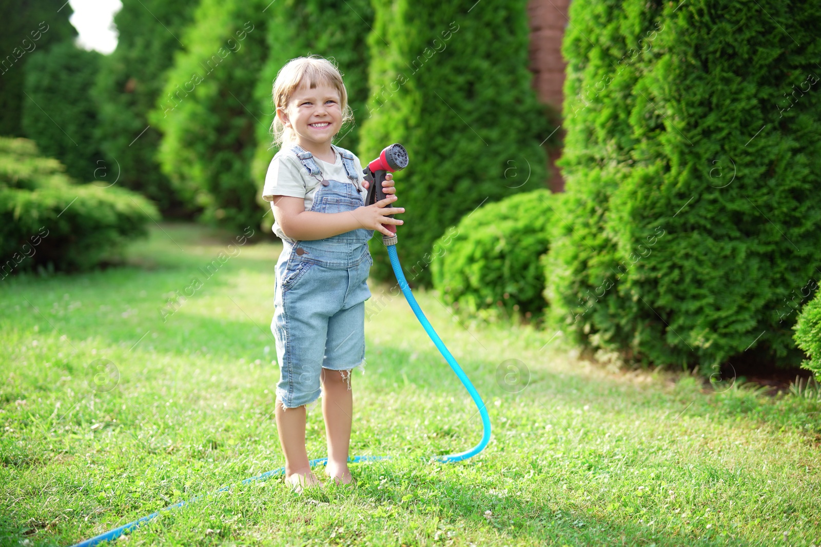 Photo of Little girl with hose in backyard, space for text