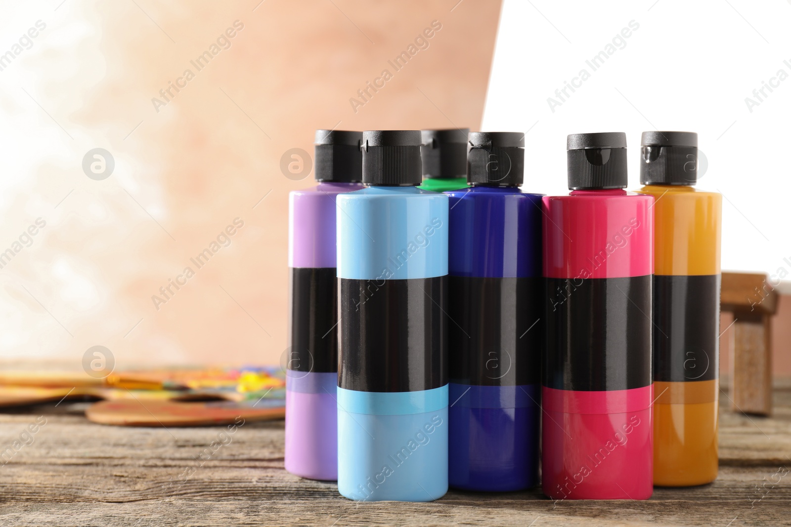 Photo of Acrylic paints of different colors in bottles on wooden table