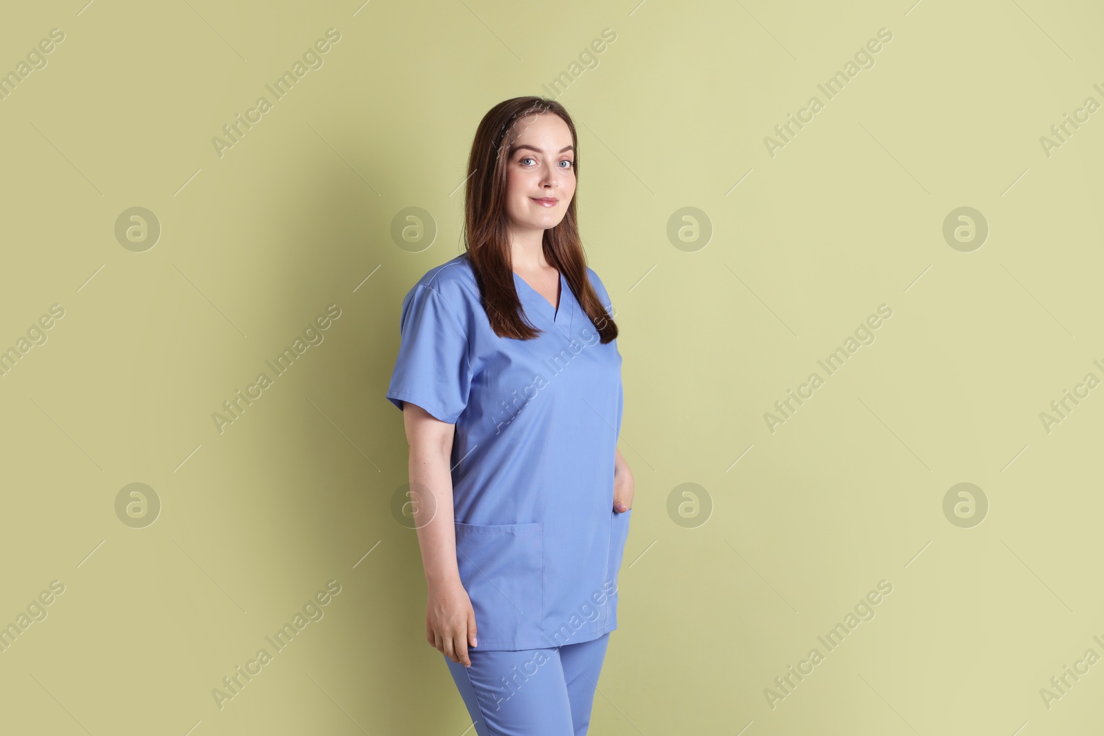 Photo of Professional nurse in uniform on pale green background