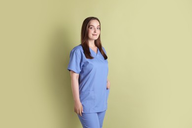 Photo of Professional nurse in uniform on pale green background