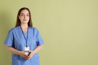 Photo of Professional nurse with badge on pale green background. Space for text