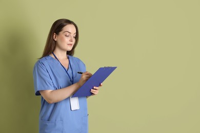 Photo of Professional nurse with clipboard on pale green background. Space for text