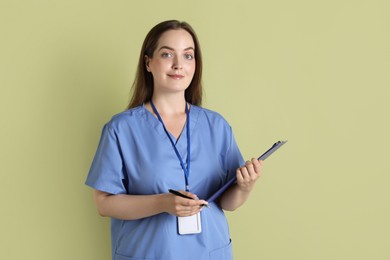 Professional nurse with clipboard on pale green background