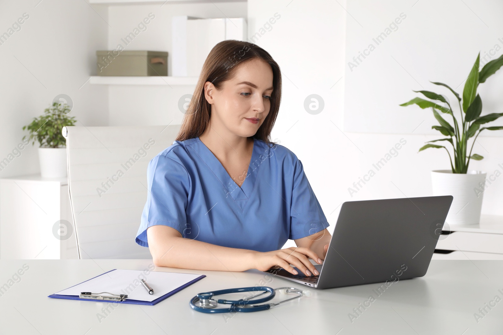 Photo of Young nurse working with laptop at desk in hospital