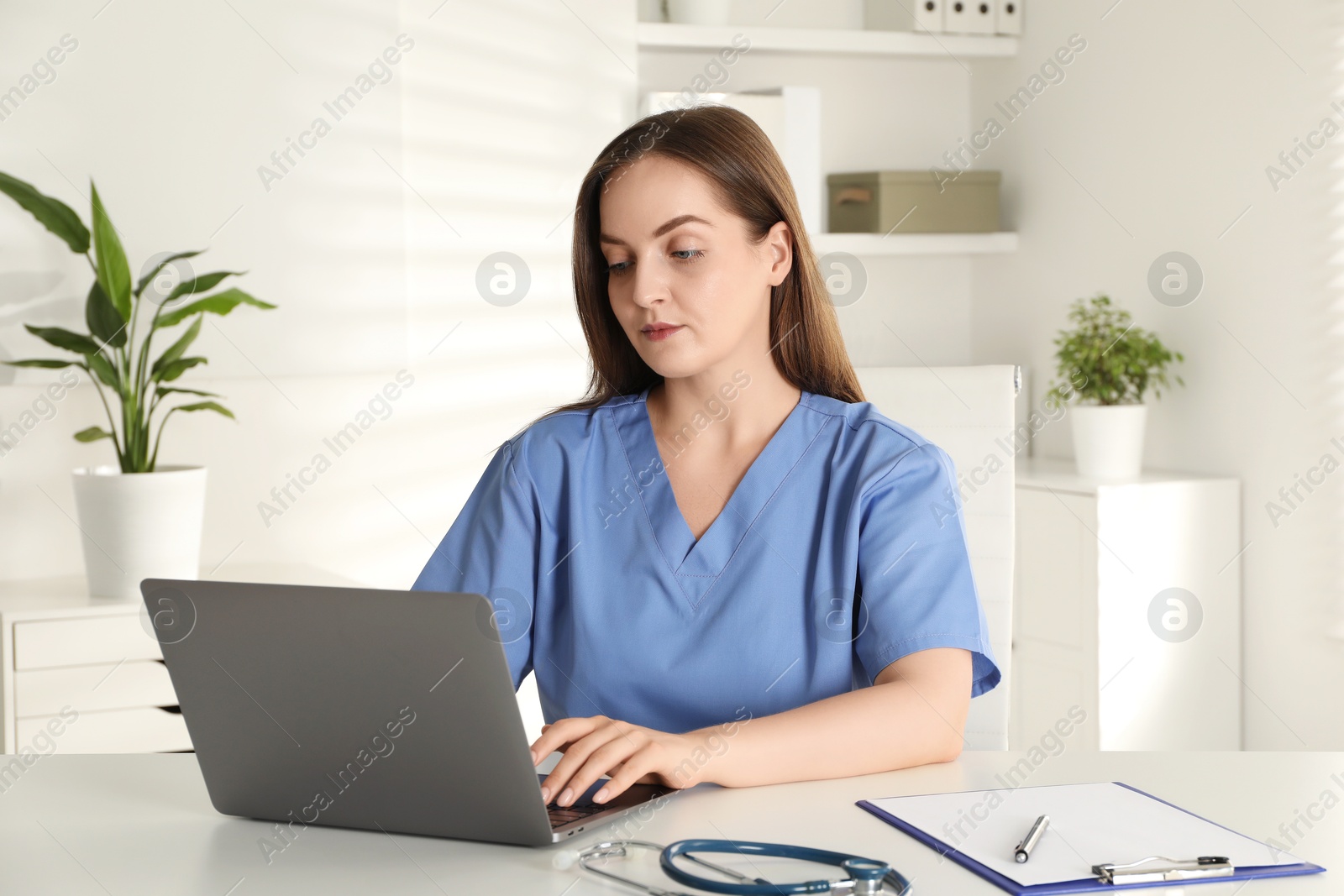 Photo of Young nurse working with laptop at desk in hospital