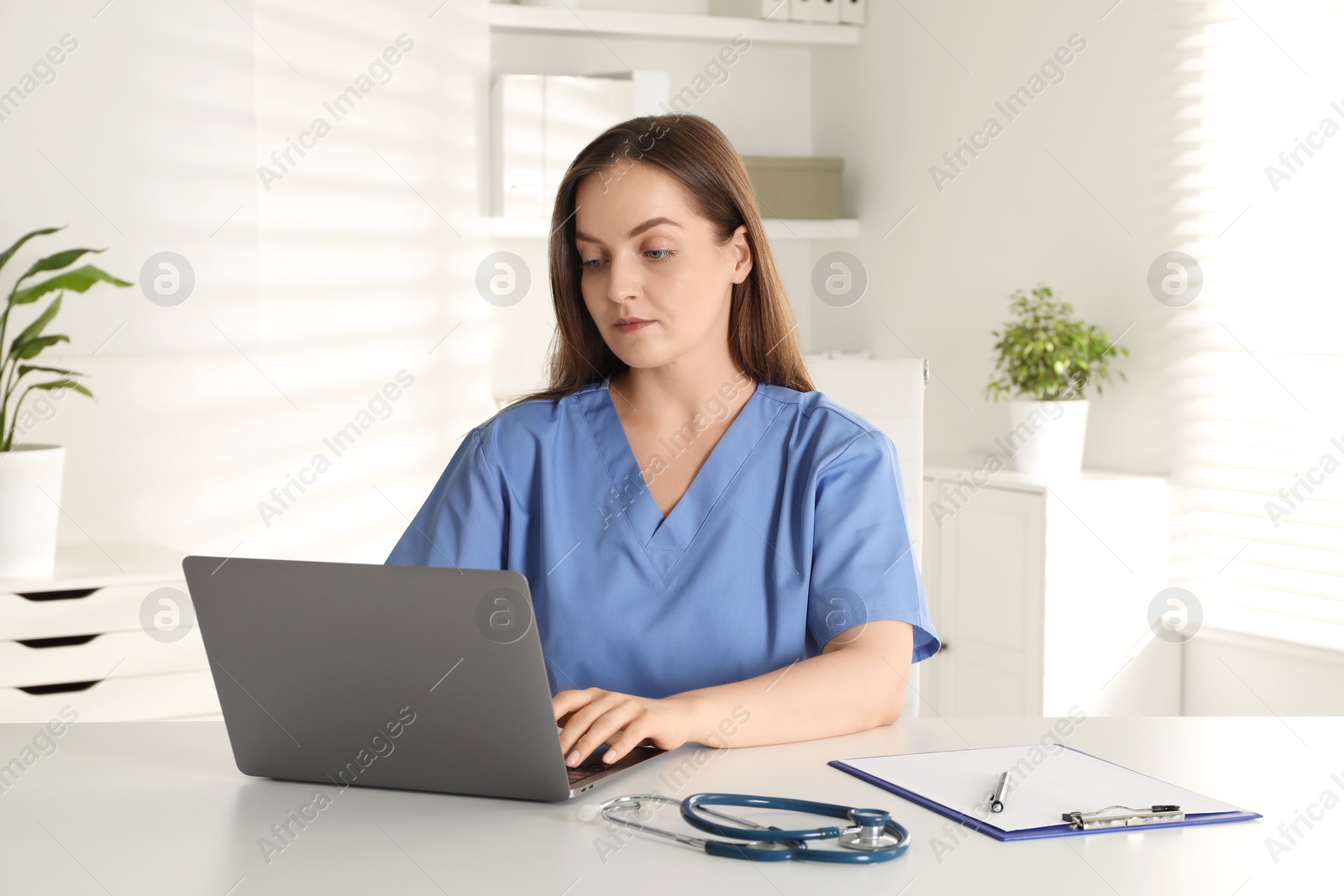 Photo of Young nurse working with laptop at desk in hospital