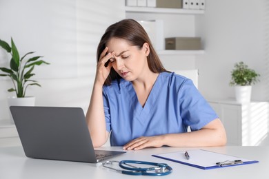 Photo of Tired nurse working at desk in hospital