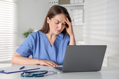 Photo of Tired nurse working at desk in hospital