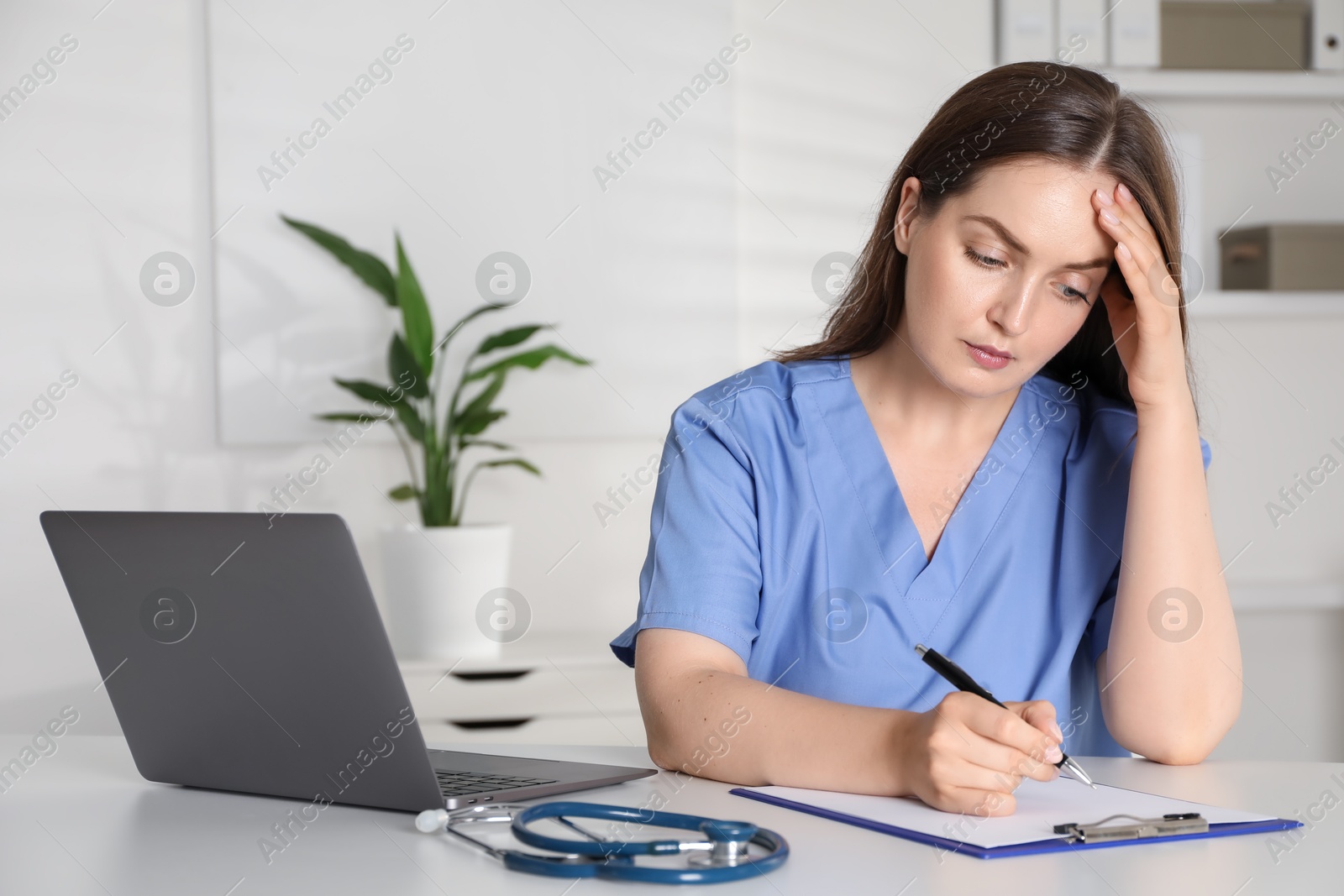 Photo of Tired nurse working at desk in hospital