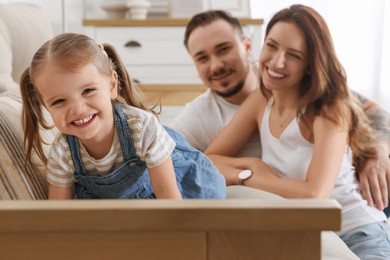 Photo of Happy family. Parents and their cute little daughter on sofa at home, selective focus