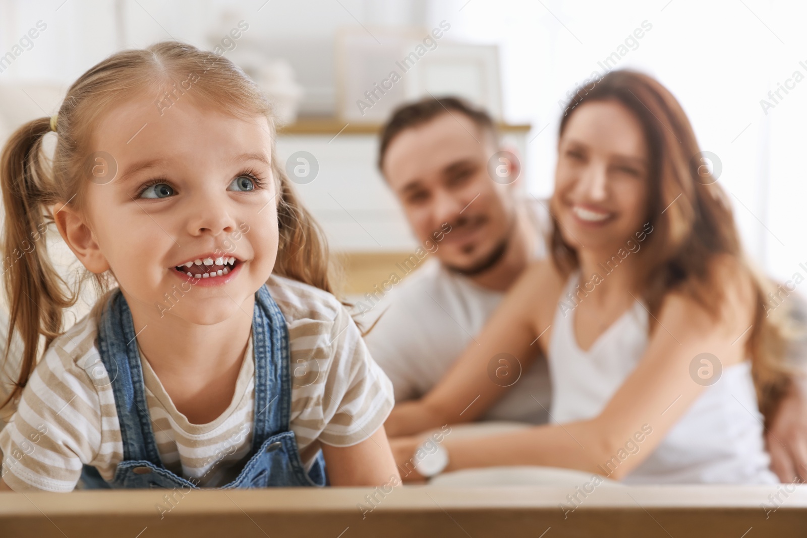 Photo of Happy family. Parents and their cute little daughter on sofa at home, selective focus