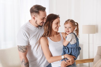 Photo of Happy family. Parents and their cute little daughter at home