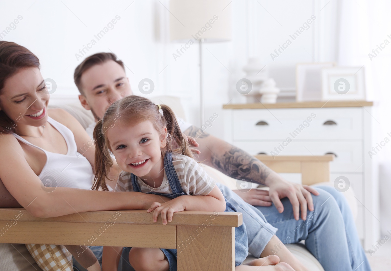 Photo of Happy family. Parents and their cute little daughter on sofa at home, selective focus