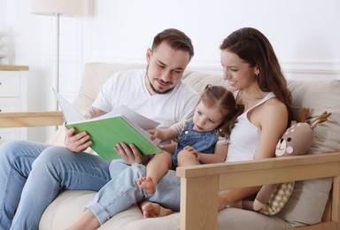 Photo of Happy family. Parents and their cute little daughter reading book at home