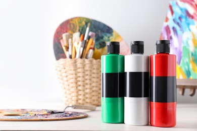 Photo of Acrylic paints of different colors, palettes, knife and brushes on wooden table