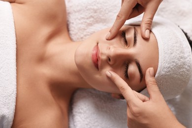 Photo of Attractive woman enjoying face massage, top view. Beauty procedure