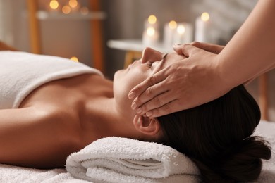 Photo of Attractive woman enjoying face massage in spa salon, closeup