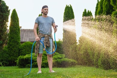 Man watering lawn with hose in backyard, low angle view