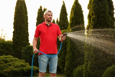 Man watering lawn with hose in backyard