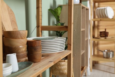 Wooden storage stand with kitchenware near green wall indoors, closeup