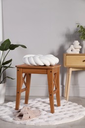 Wooden stool with knot cushion in room. Stylish interior design