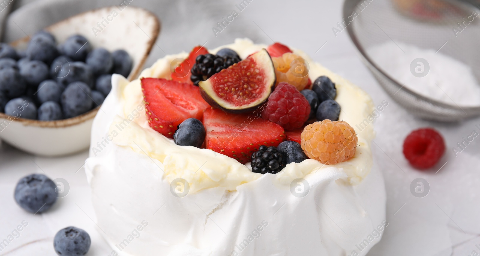 Photo of Pavlova cake (meringue dessert) with whipped cream, fresh berries and fig on table, closeup