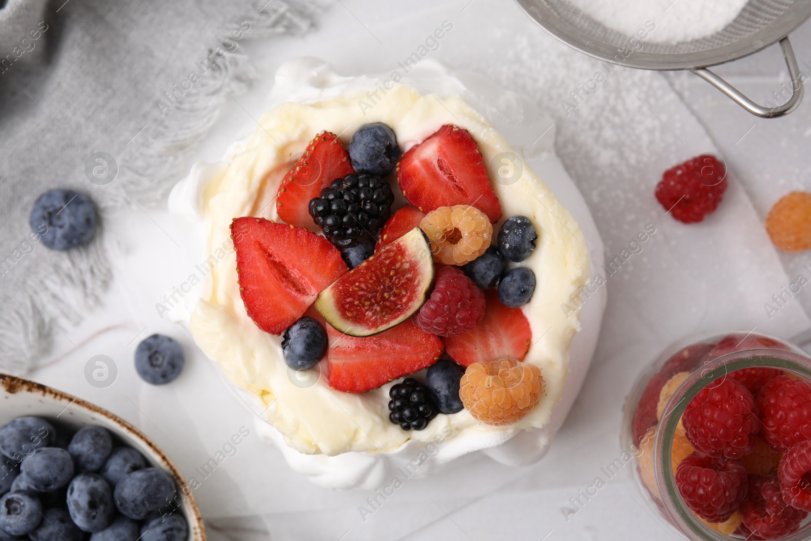 Photo of Pavlova cake (meringue dessert) with whipped cream, fresh berries and fig on table, flat lay