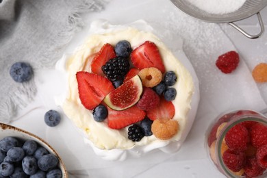 Photo of Pavlova cake (meringue dessert) with whipped cream, fresh berries and fig on table, flat lay