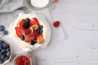 Photo of Pavlova cake (meringue dessert) with whipped cream, fresh berries and fig on white table, flat lay. Space for text