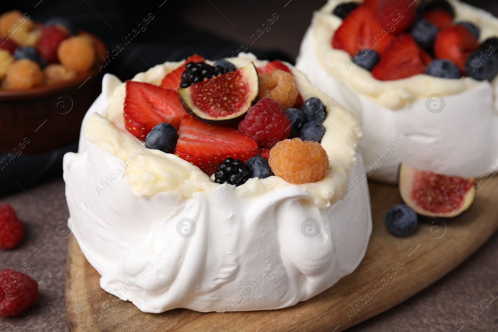 Photo of Pavlova cake (meringue dessert) with whipped cream, fresh berries and fig on brown table, closeup