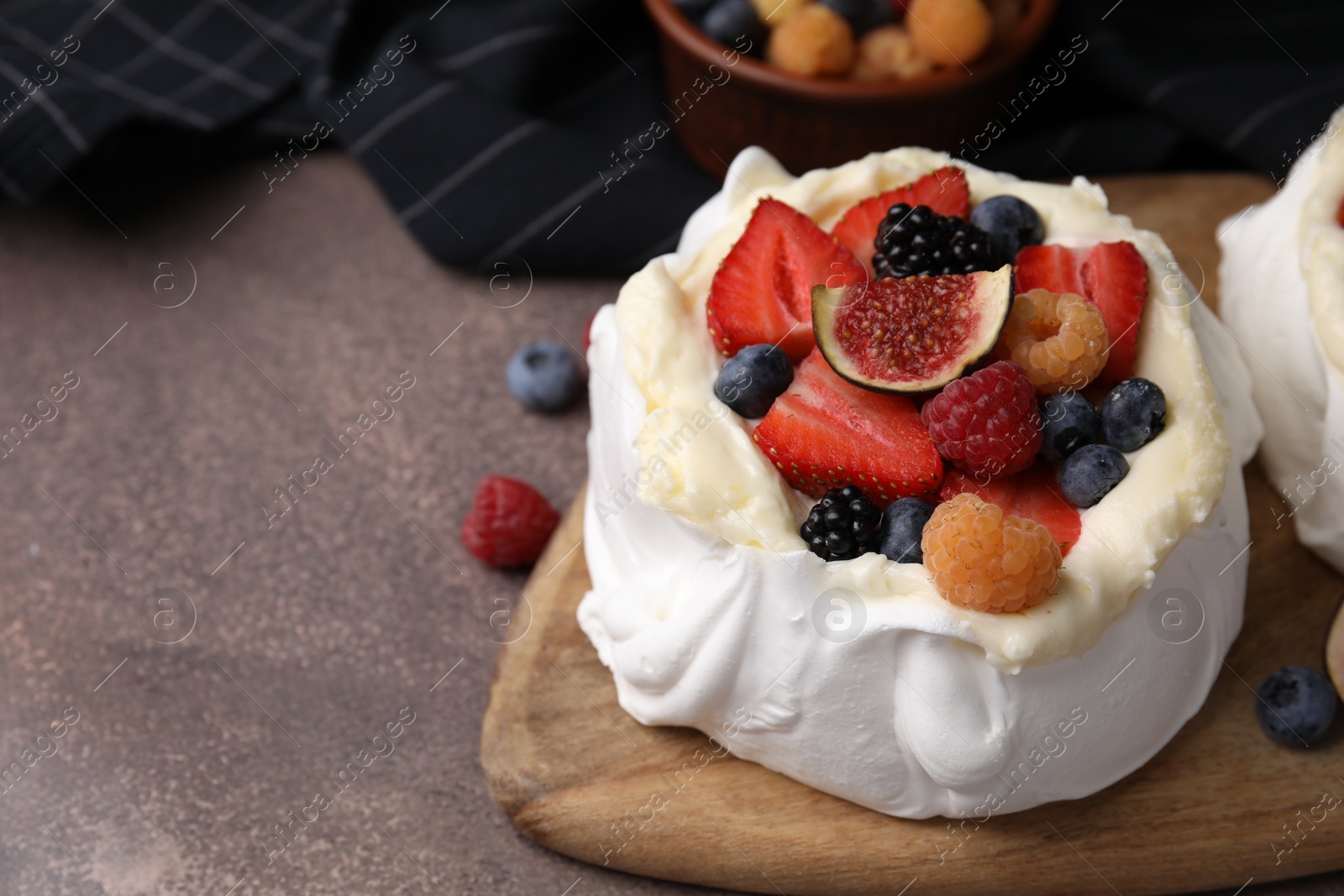 Photo of Pavlova cake (meringue dessert) with whipped cream, fresh berries and fig on brown table, closeup. Space for text