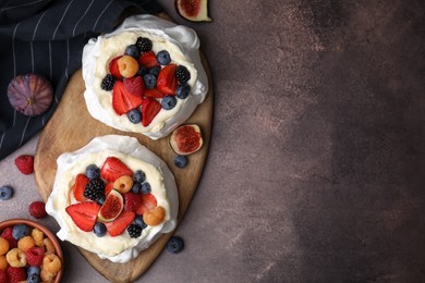 Photo of Pavlova cake (meringue dessert) with whipped cream, fresh berries and fig on brown table, flat lay. Space for text