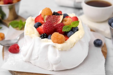 Photo of Pavlova cake (meringue dessert) with whipped cream, fresh berries, fig and mint on table, closeup