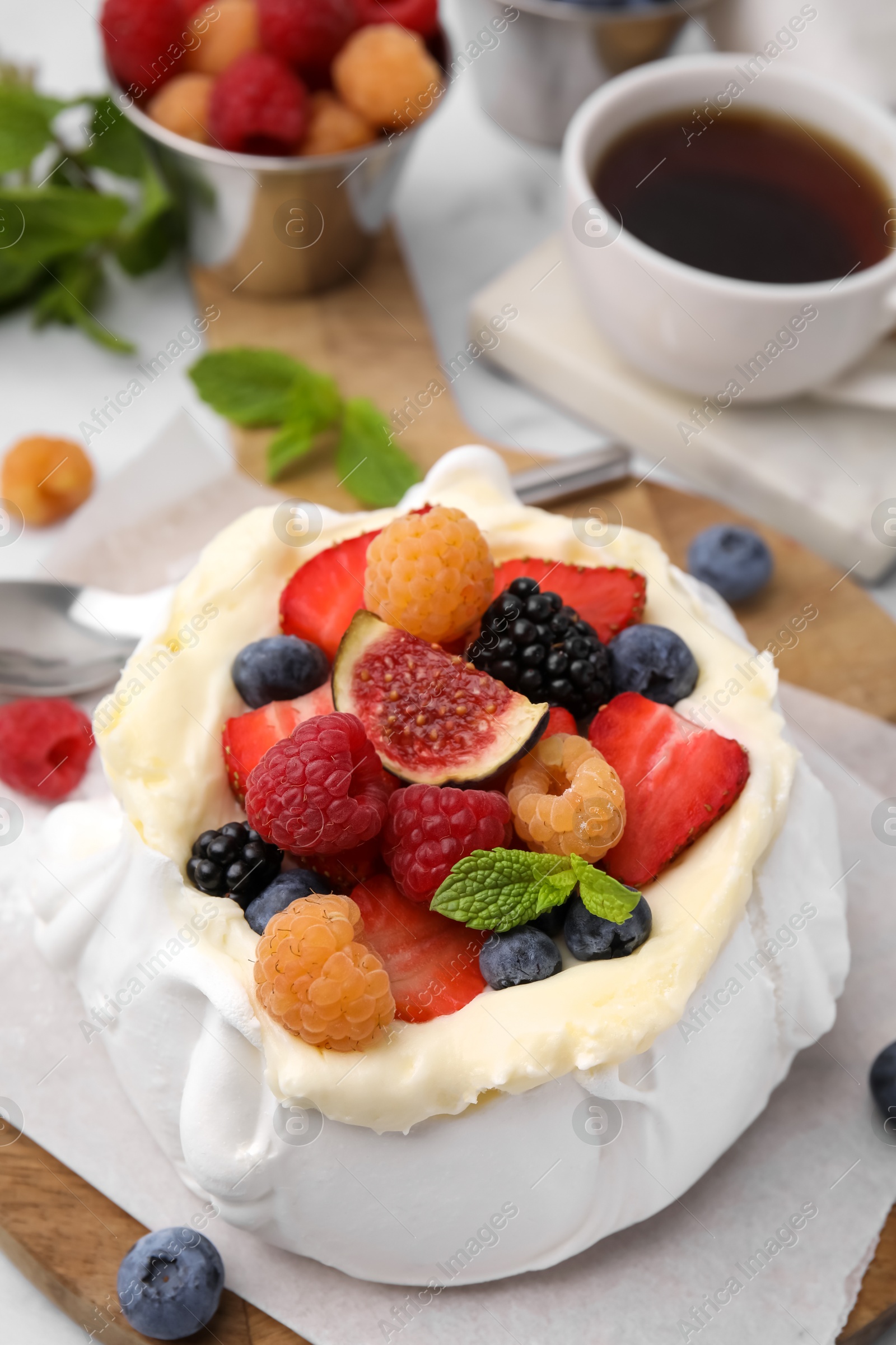 Photo of Pavlova cake (meringue dessert) with whipped cream, fresh berries, fig and mint on table, closeup