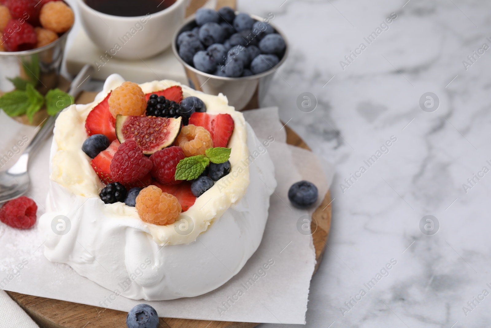 Photo of Pavlova cake (meringue dessert) with whipped cream, fresh berries, fig and mint on white marble table, closeup