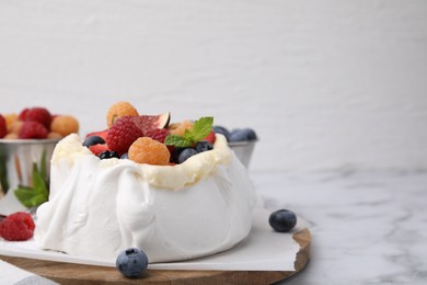 Photo of Pavlova cake (meringue dessert) with whipped cream, fresh berries, fig and mint on white marble table, closeup