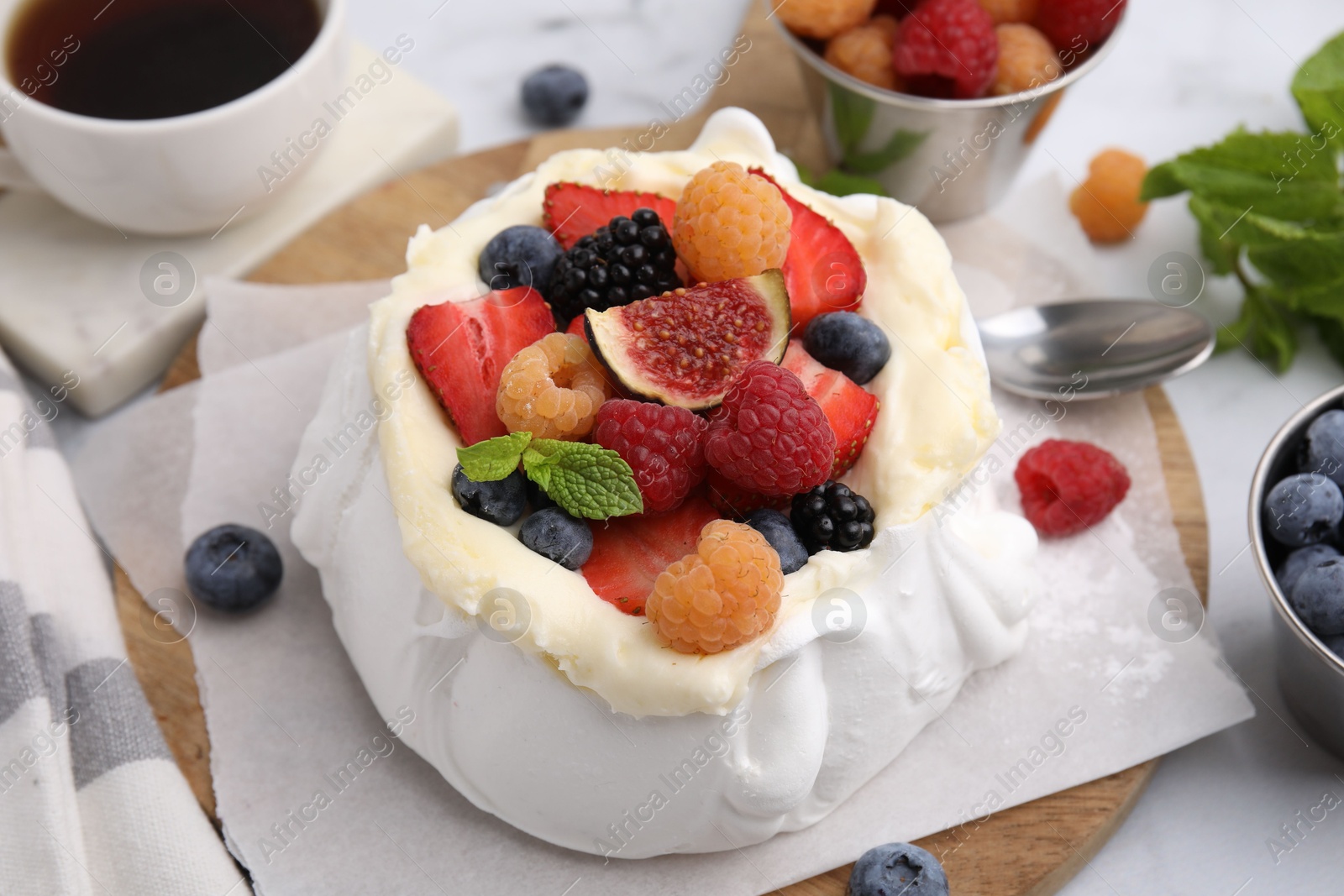 Photo of Pavlova cake (meringue dessert) with whipped cream, fresh berries, fig and mint on table, closeup