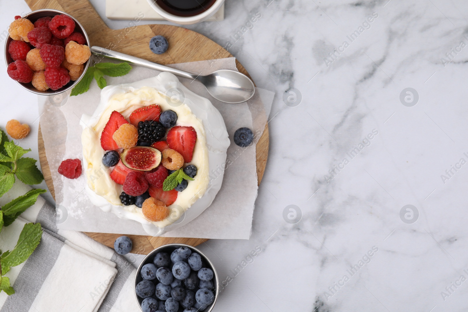 Photo of Pavlova cake (meringue dessert) with whipped cream, fresh berries, fig and mint on white marble table, flat lay. Space for text