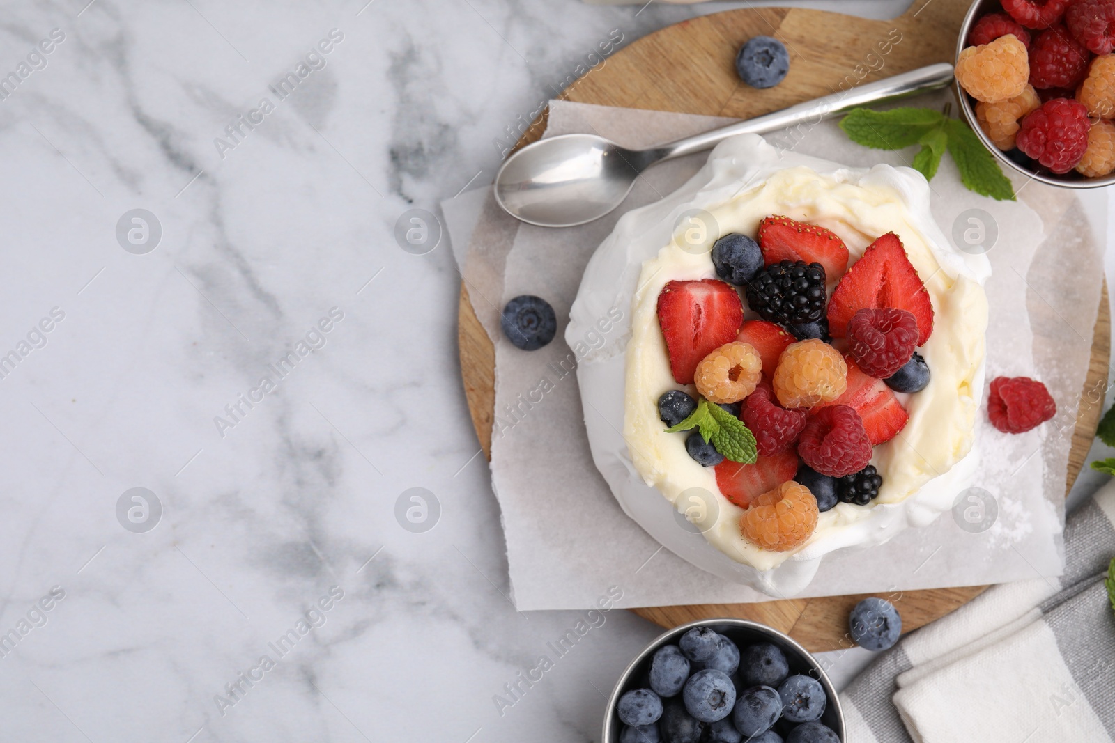 Photo of Pavlova cake (meringue dessert) with whipped cream, fresh berries and mint on white marble table, flat lay. Space for text