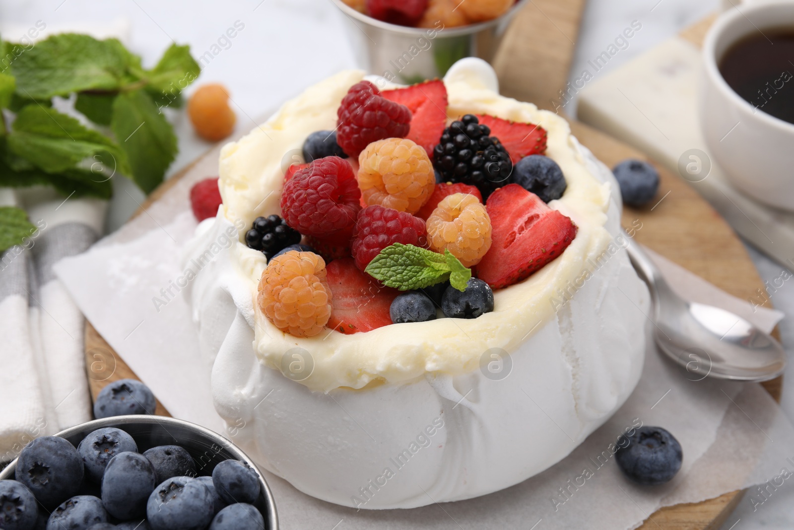 Photo of Pavlova cake (meringue dessert) with whipped cream, fresh berries and mint on table, closeup