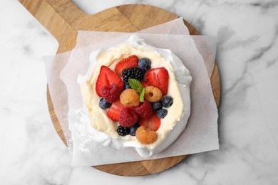 Photo of Pavlova cake (meringue dessert) with whipped cream, fresh berries and mint on white marble table, top view