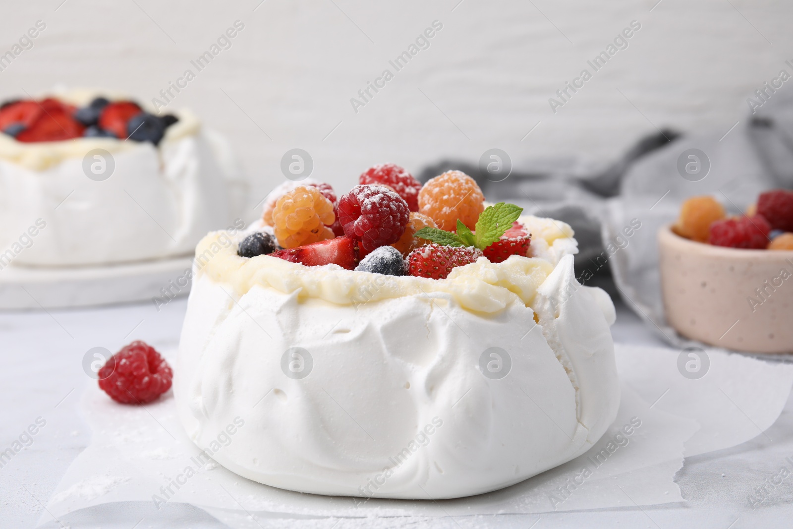 Photo of Pavlova cake (meringue dessert) with whipped cream, fresh berries, powdered sugar and mint on table, closeup