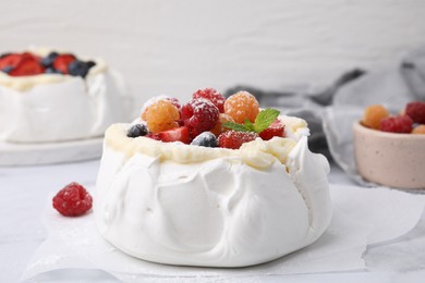 Photo of Pavlova cake (meringue dessert) with whipped cream, fresh berries, powdered sugar and mint on table, closeup