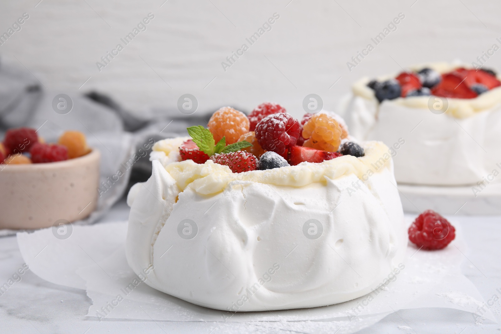 Photo of Pavlova cake (meringue dessert) with whipped cream, fresh berries, powdered sugar and mint on table, closeup